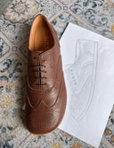 Zapato Oxford barefoot marrón de SHUU junto a su boceto