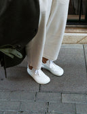 Bamba blanca de piel combinada con jogger beige y abrigo verde. Calzado barefoot SHUU Barefoot. Hecho en España