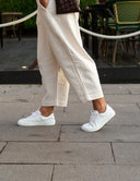 Deportiva casual barefoot en piel blanca en una chica caminando por una terraza. Calzado Barefoot SHUU Barefoot.