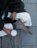 Botín chelsea de piel topo combinado con pantalón blanco y abrigo verde. Calzado Barefoot SHUU Barefoot.